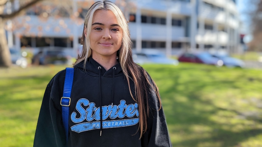 A portrait of Tash Peterson taken outside with green grass and a building in the background