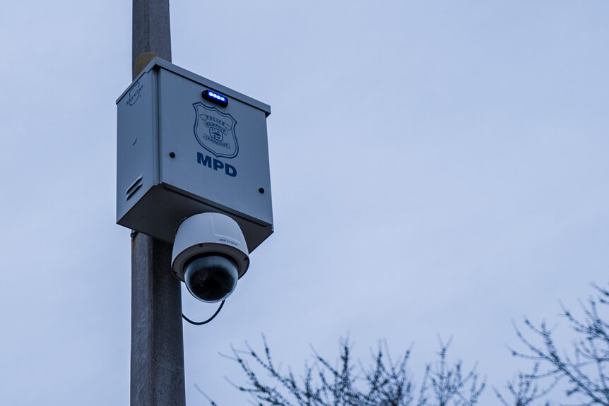 A pole with a police security camera attatched to it.