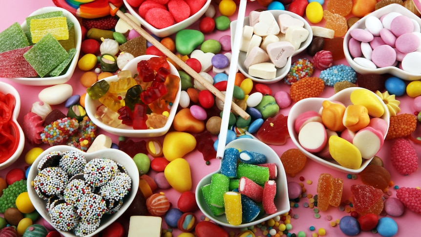 Top-down view of table covered in colouful assortment of sugary treats and chocolates