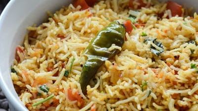 A bowl of tomato rice in a white bowl with beans and sprices