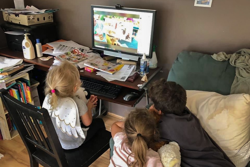 Three children crowd round a computer screen