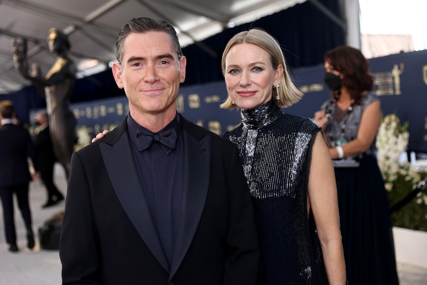 Naomi Watts and Billy Crudup standing side by side dressed formally and outside at an awards show