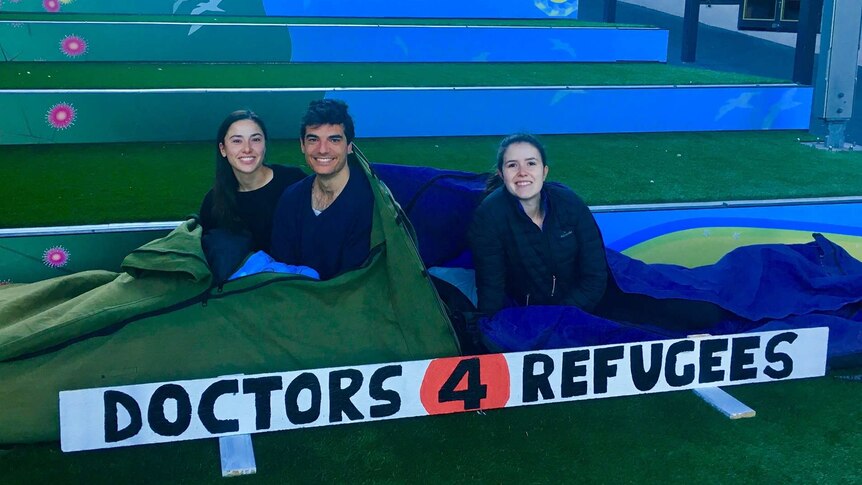 Three people in swags getting ready to sleep-out in Wollongong Mall