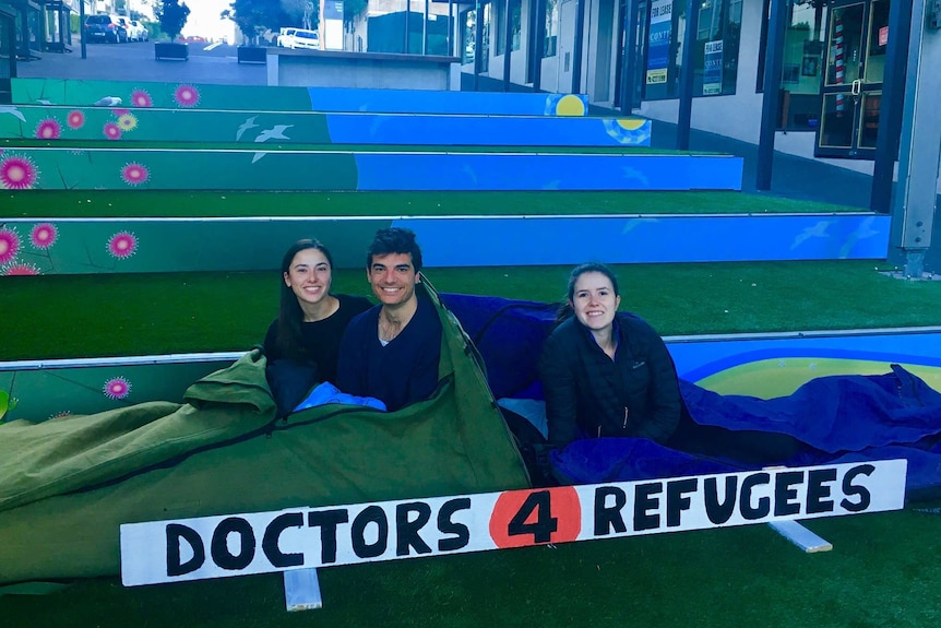 Three people in swags getting ready to sleep-out in Wollongong Mall