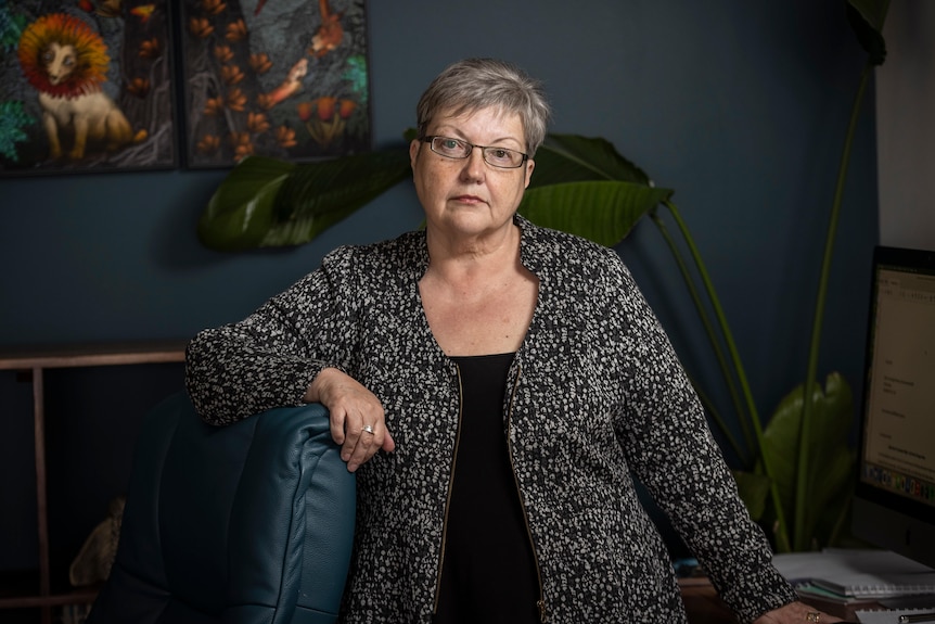 A woman poses for a photo in a chair inside an office