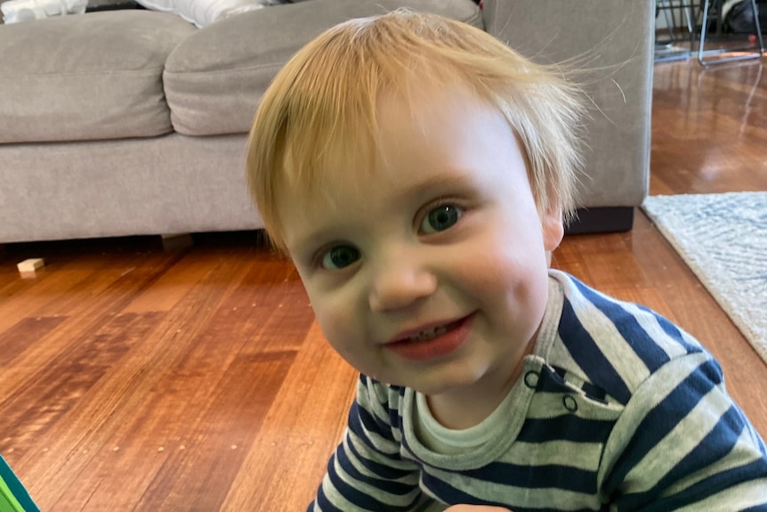 Toddler Noah Souvatzis sitting on the floor at home