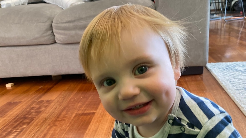 Toddler Noah Souvatzis sitting on the floor at home