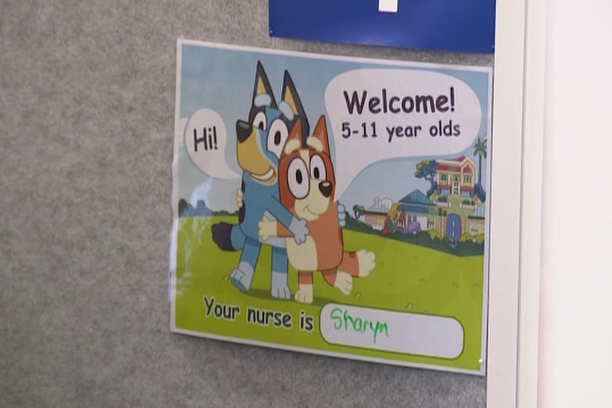 A sign with two cartoon dogs on a cubicle wall