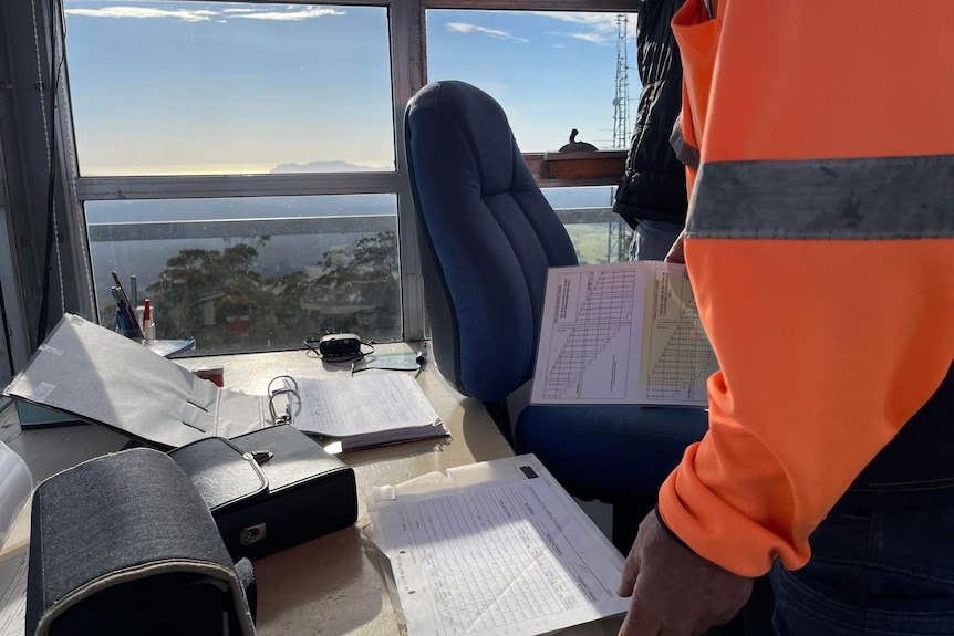 A desk in a tower, a man in high vis standing over it