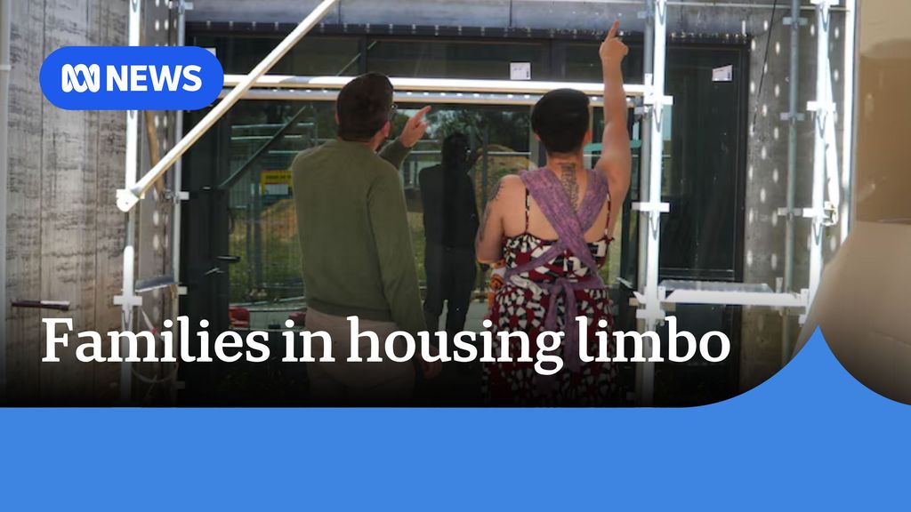 Families in housing limbo: A man and woman point up while standing in a construction site.