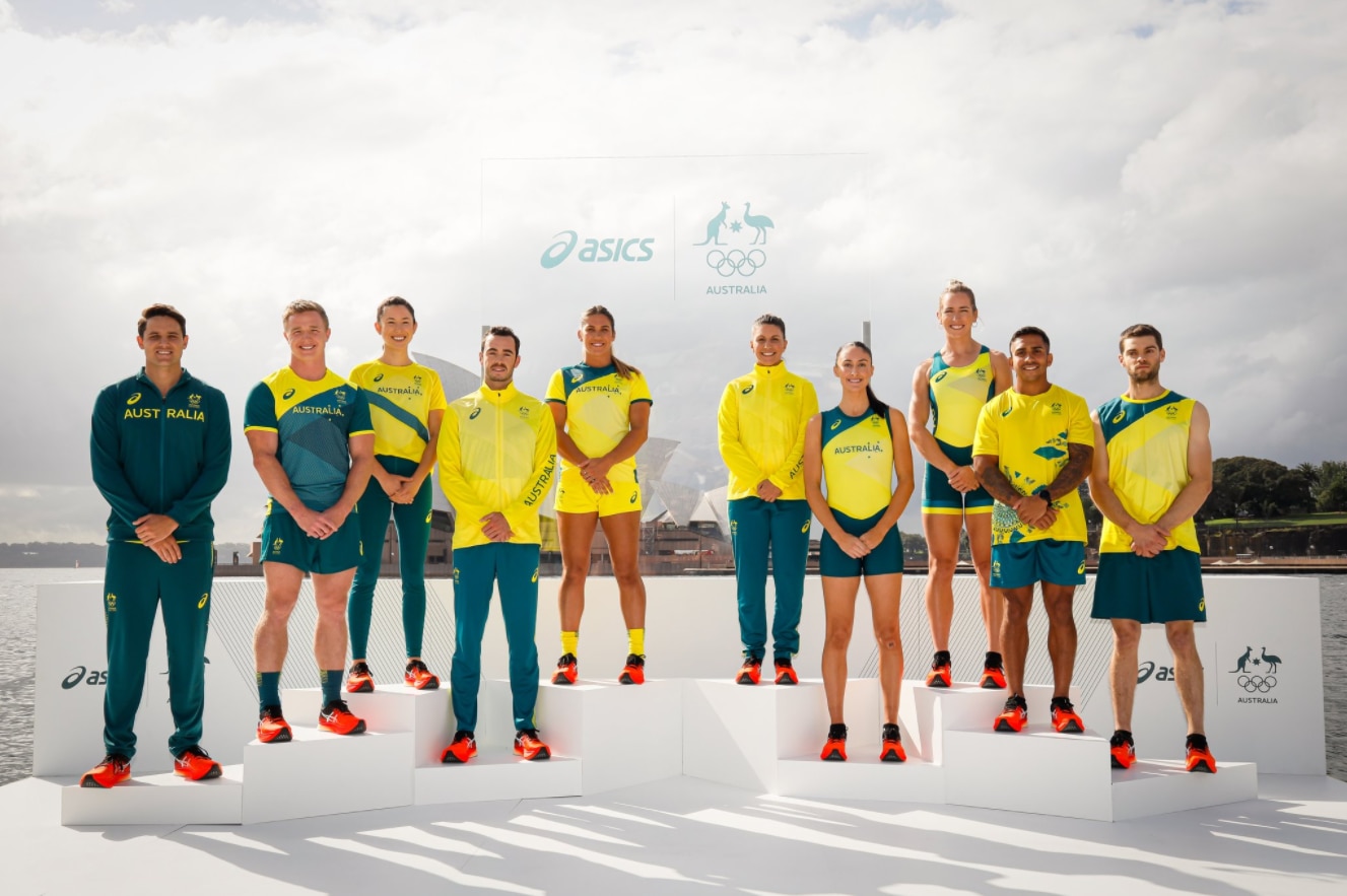 A group of athletes standing on a podium at the unveiling of a team uniform.   