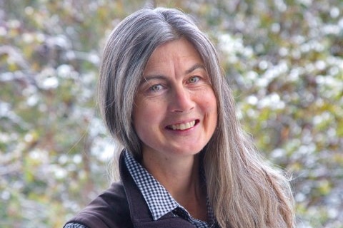woman with grey hair in check shirt and vest
