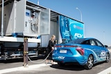 A woman refuels a hydrogen fuel cell car