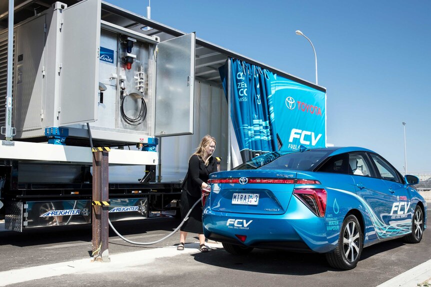 A woman refuels a hydrogen fuel cell car.