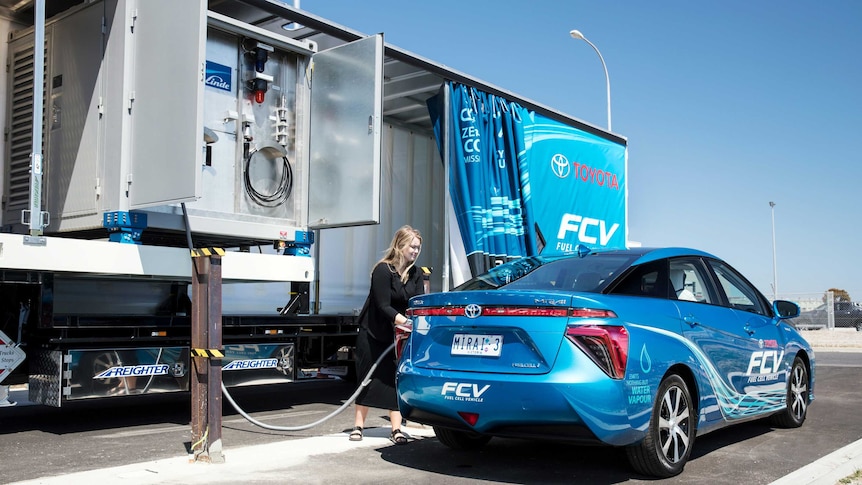 A woman refuels a hydrogen fuel cell car.