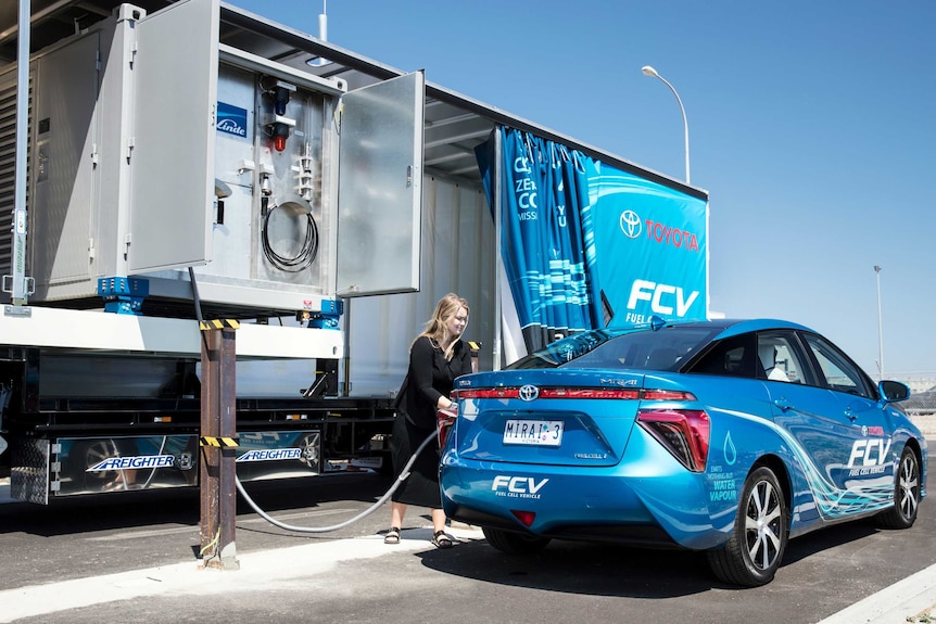 A woman refuels a hydrogen fuel cell car