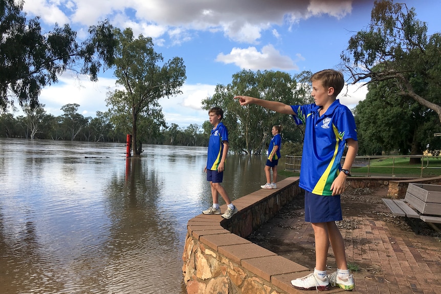 School students point towards the swollen river from its bank.