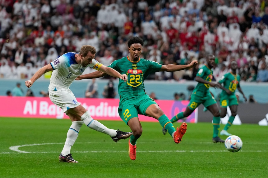 England striker hits a right-foot shot towards goal as a Senegal defender tries to block the ball.