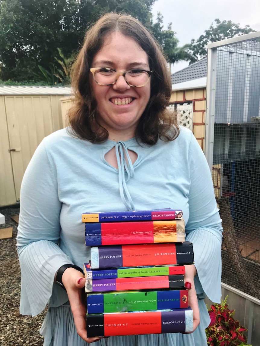 Rebecca Sharrock holds a pile of Harry Potter books.
