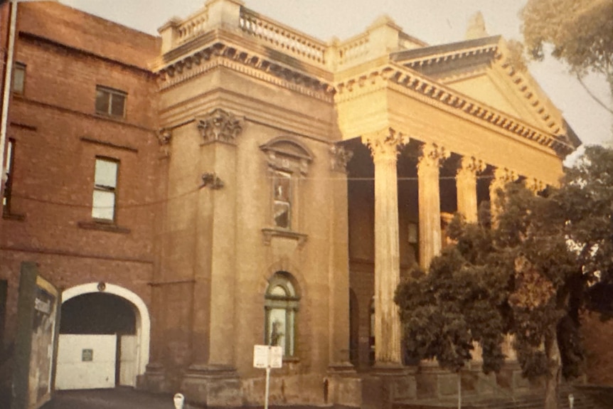 A sepia-toned photograph of the outside of a theatre, with Corinthian columns out the front.