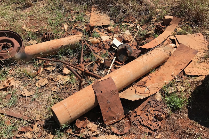 Old building materials, piping with asbestos strewn over the ground.