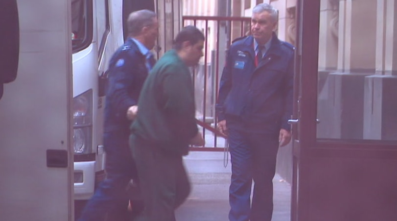 Mohamed Naddaf, wearing a green outfit, is escorted from a prison van at the Victorian Supreme Court