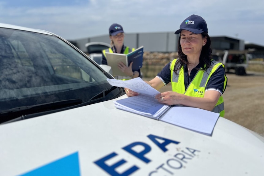EPA workers look at paper in high vis.