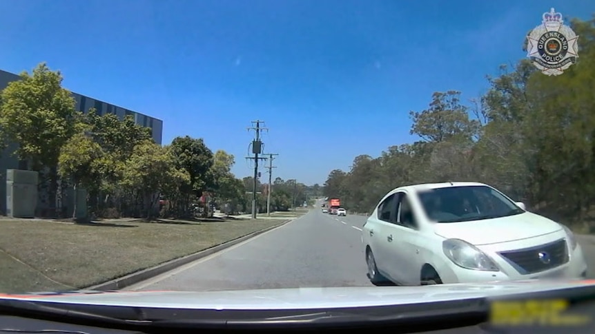 A car driving at speed towards a police car on the wrong side of the road.