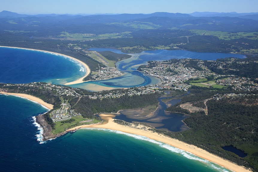 A drone shot of a coastline with river going up the middle.