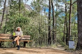 woman sits on beach bench with mountain in background