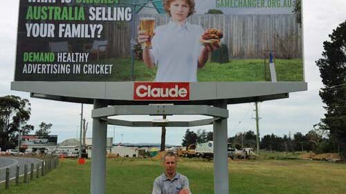 Tasmanian man Aaron Schultz stands in front of an anti-junk food billboard in Hobart.