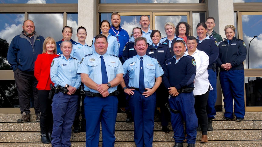 A group of police officers pose for a group photo on the steps of a function centre.