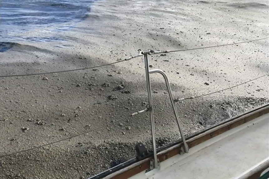 A yacht sailing through the ocean filled with floating pumice