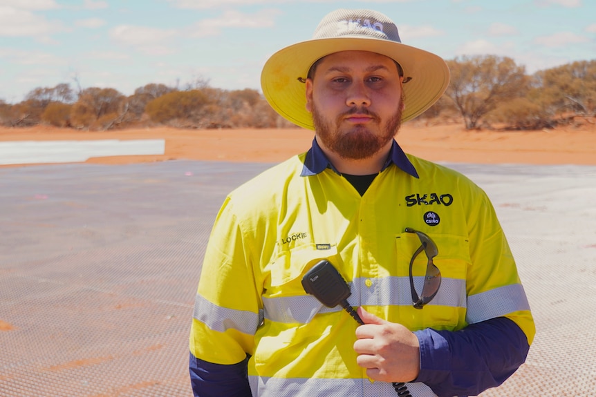 Lockie Ronan in a high-vis shirt, standing in front of a mesh floor in the outback.