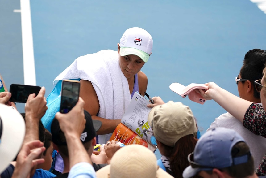 A female tennis player signs autographs at the Australian Open.