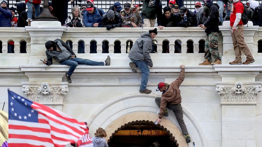 People scale a wall at Capitol Hill in Washington DC