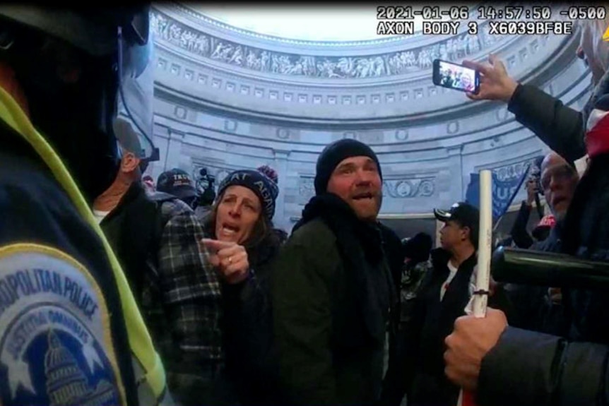 A man and woman speaking to riot police inside the Capitol Hill rotunda 