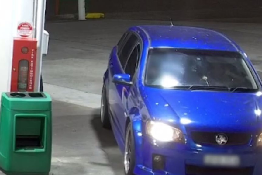CCTV footage of a blue car at a service station at night.