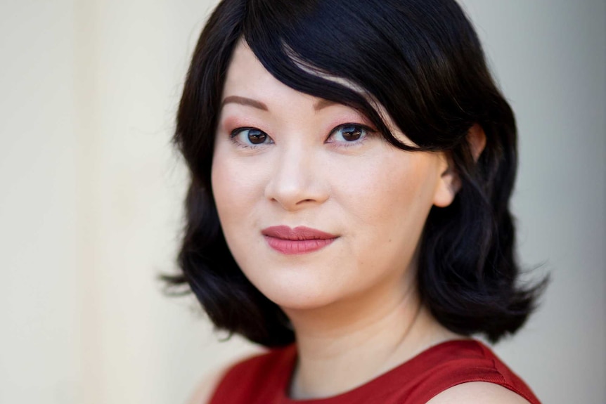 The writer Michelle Law with red lipstick and a red top, smiling in a portrait