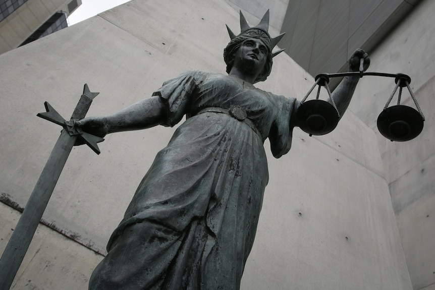 A man hits a gavel on bench in a courtroom