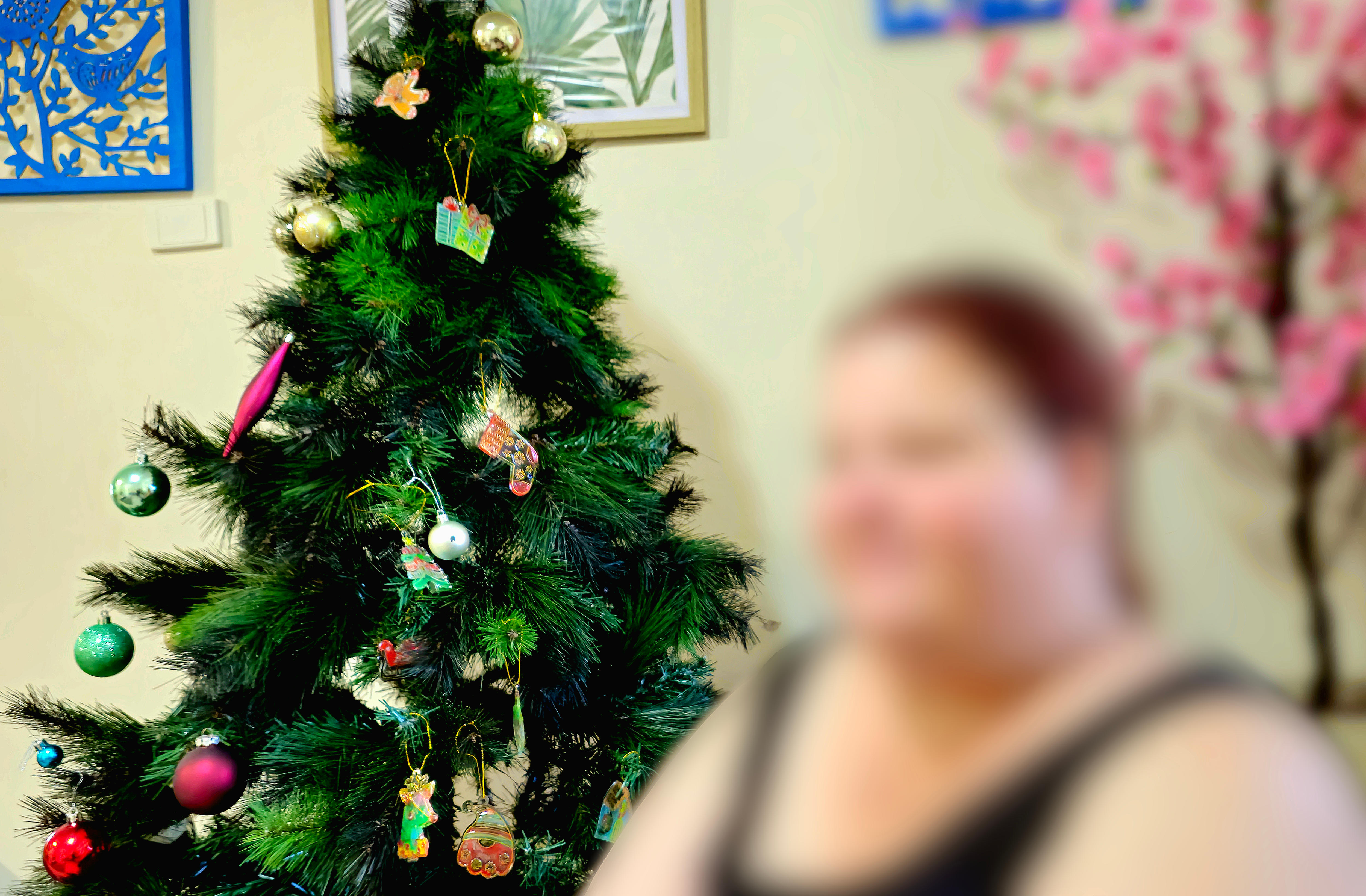 A blurred out woman sits in front of a Christmas tree