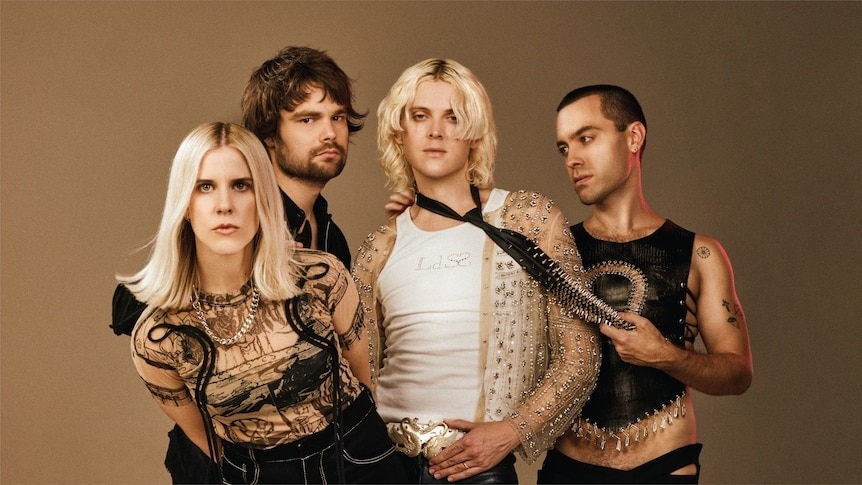 A band of four people poses against a beige backdrop.