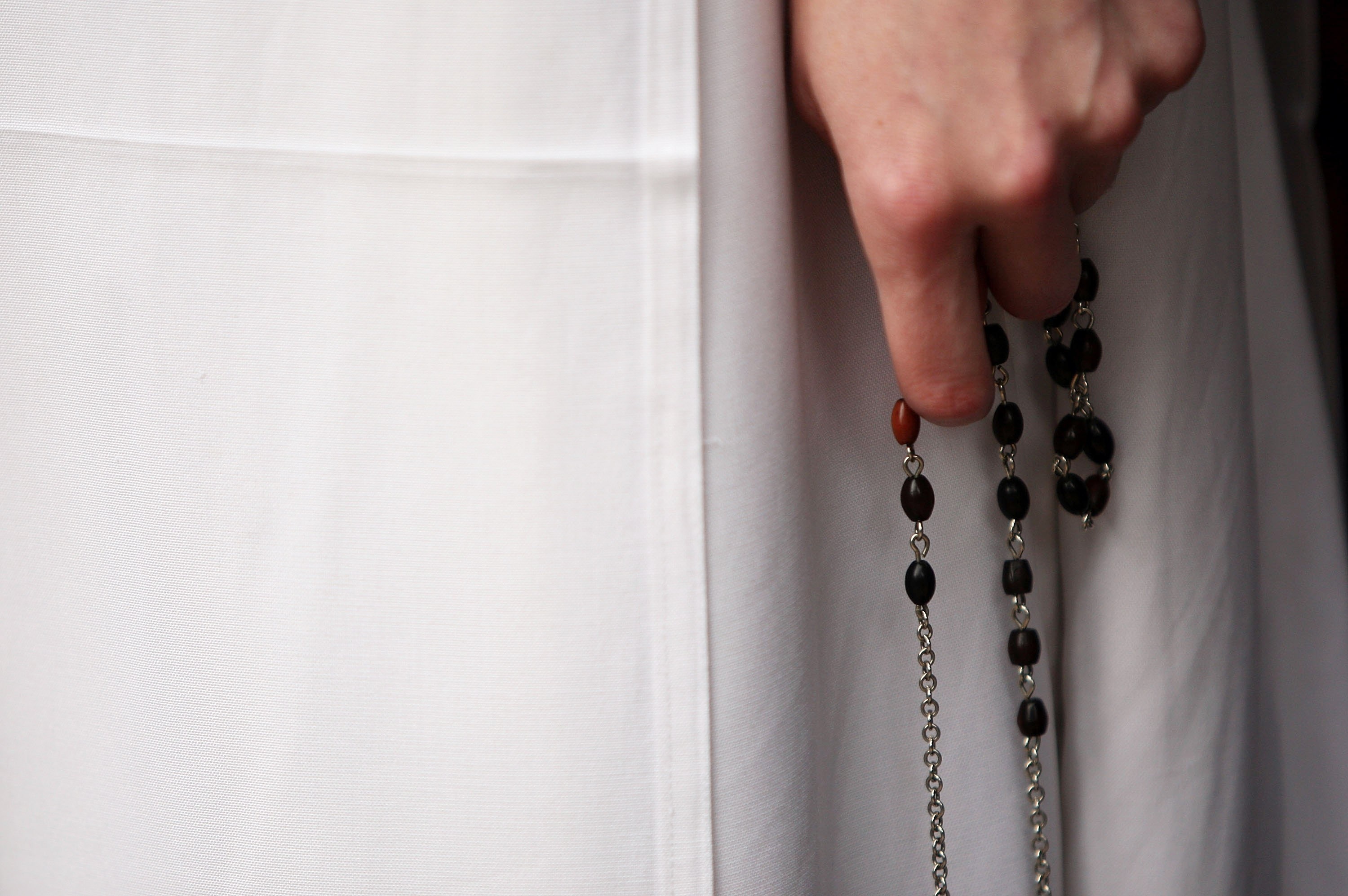 A religious sister holds rosary beads