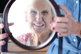 Smiling older woman looks into mirror