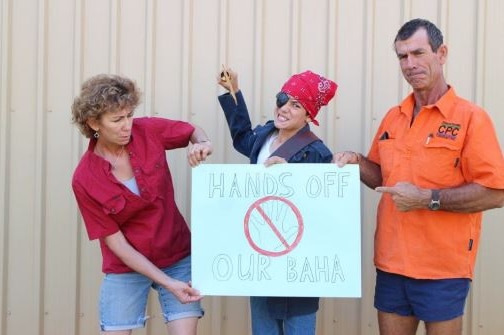Pilbara parents Robin and Evan Pensini stand either side of son Preston as he holds a sign wearing a bandana and eye patch.