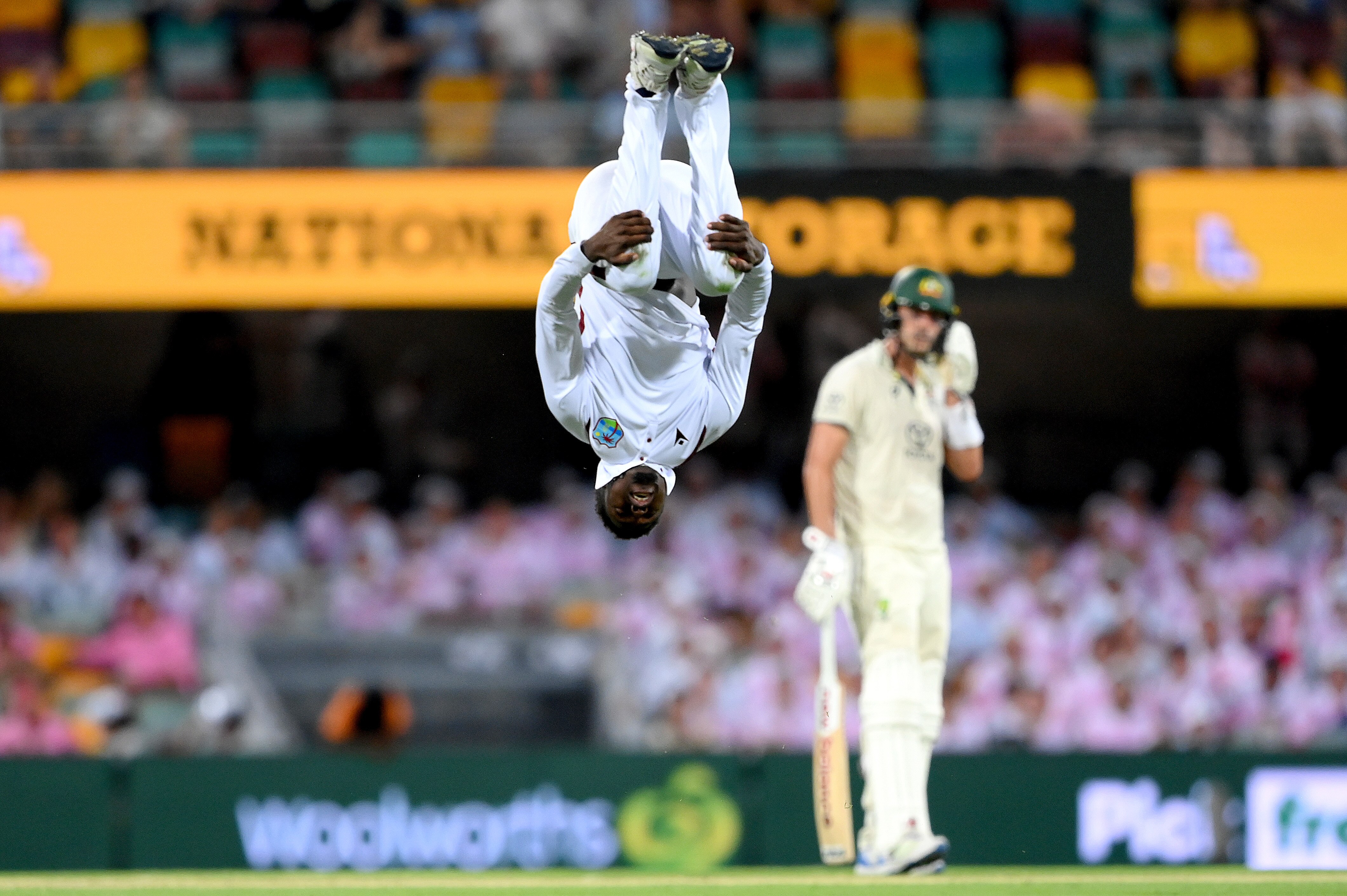 Kevin Sinclair is upside down, mid backflip after taking a wicket