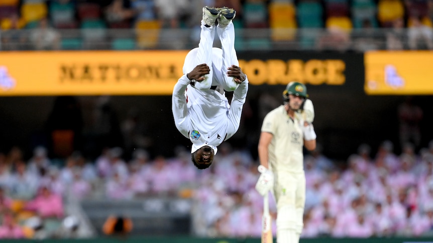 Kevin Sinclair is upside down, mid backflip after taking a wicket