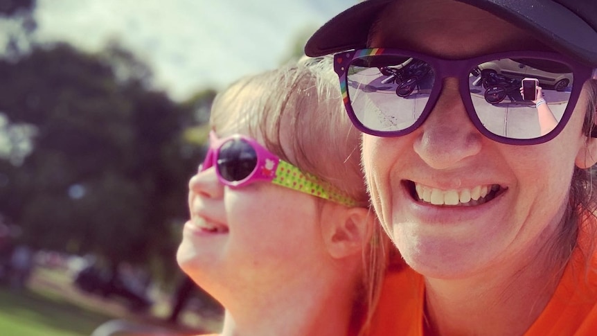 A young girl and her mother are close together and smiling.