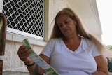 woman with blonde hair sits and looks at shopping docket