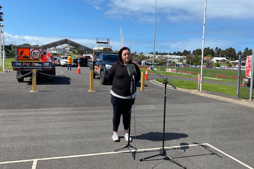 Woman standing with microphones at press conference